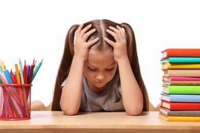 Photo of Little girl with stationery and stack of books suffering from dyslexia at wooden table