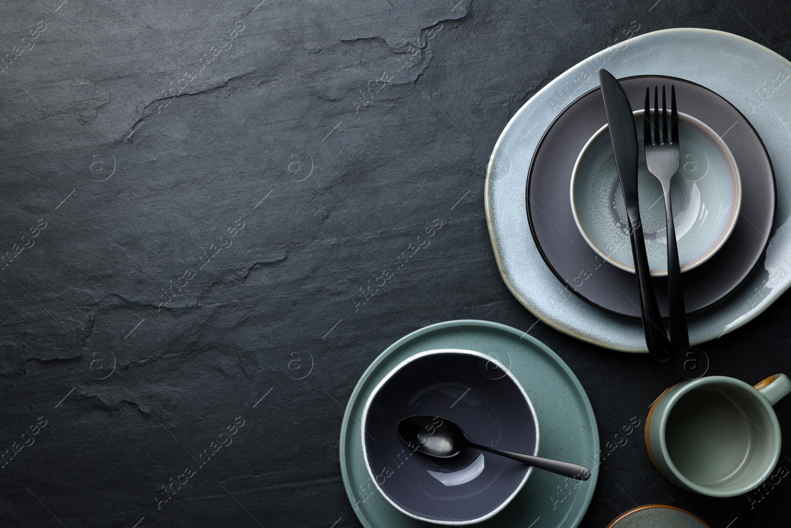 Photo of Set of clean tableware on black table, flat lay. Space for text