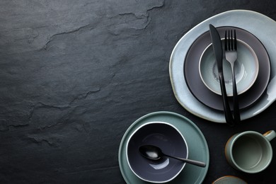 Set of clean tableware on black table, flat lay. Space for text