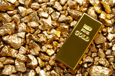 Photo of Shiny gold ingot on nuggets, top view. Space for text