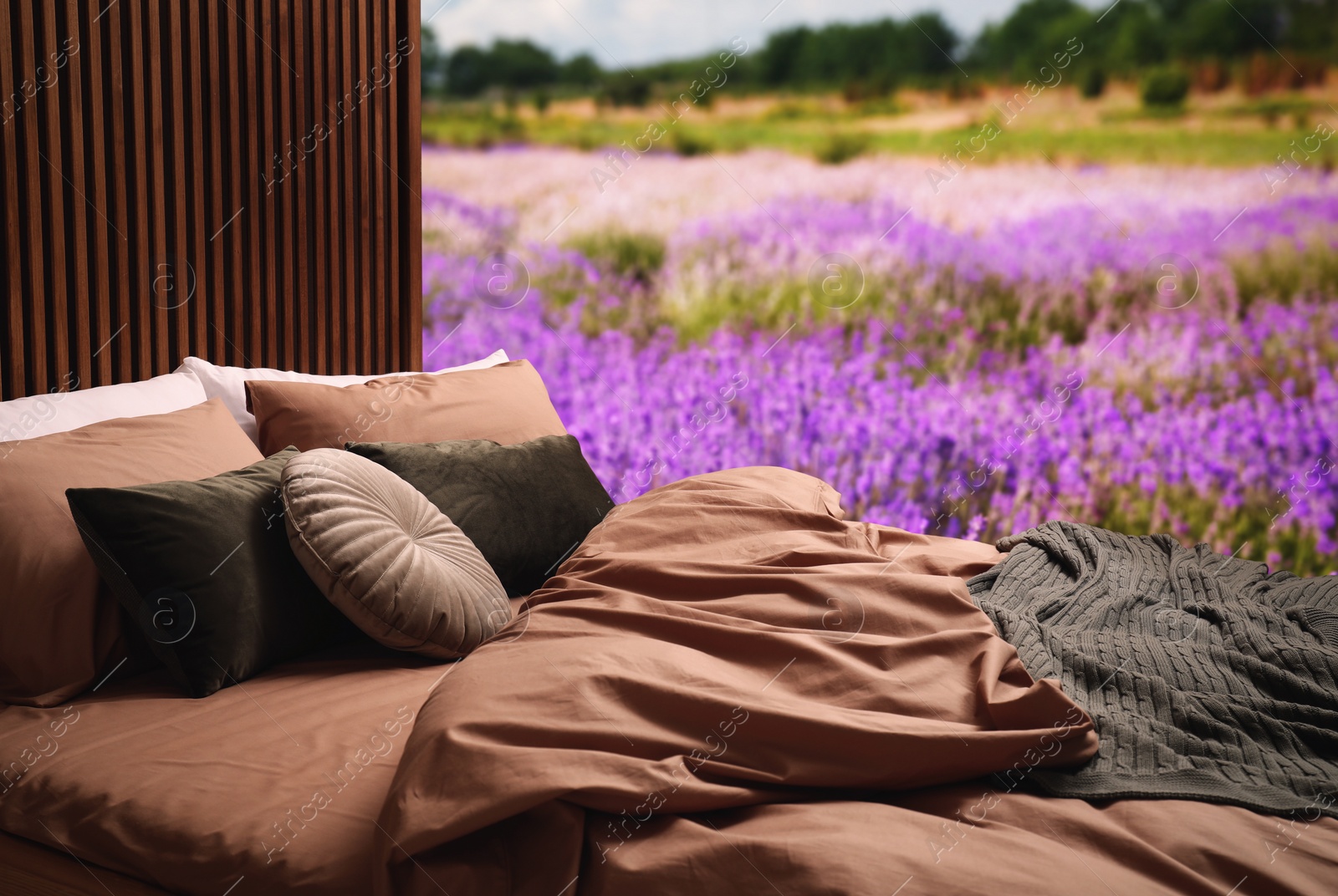 Image of Comfortable bed with soft pillows in lavender field on sunny day