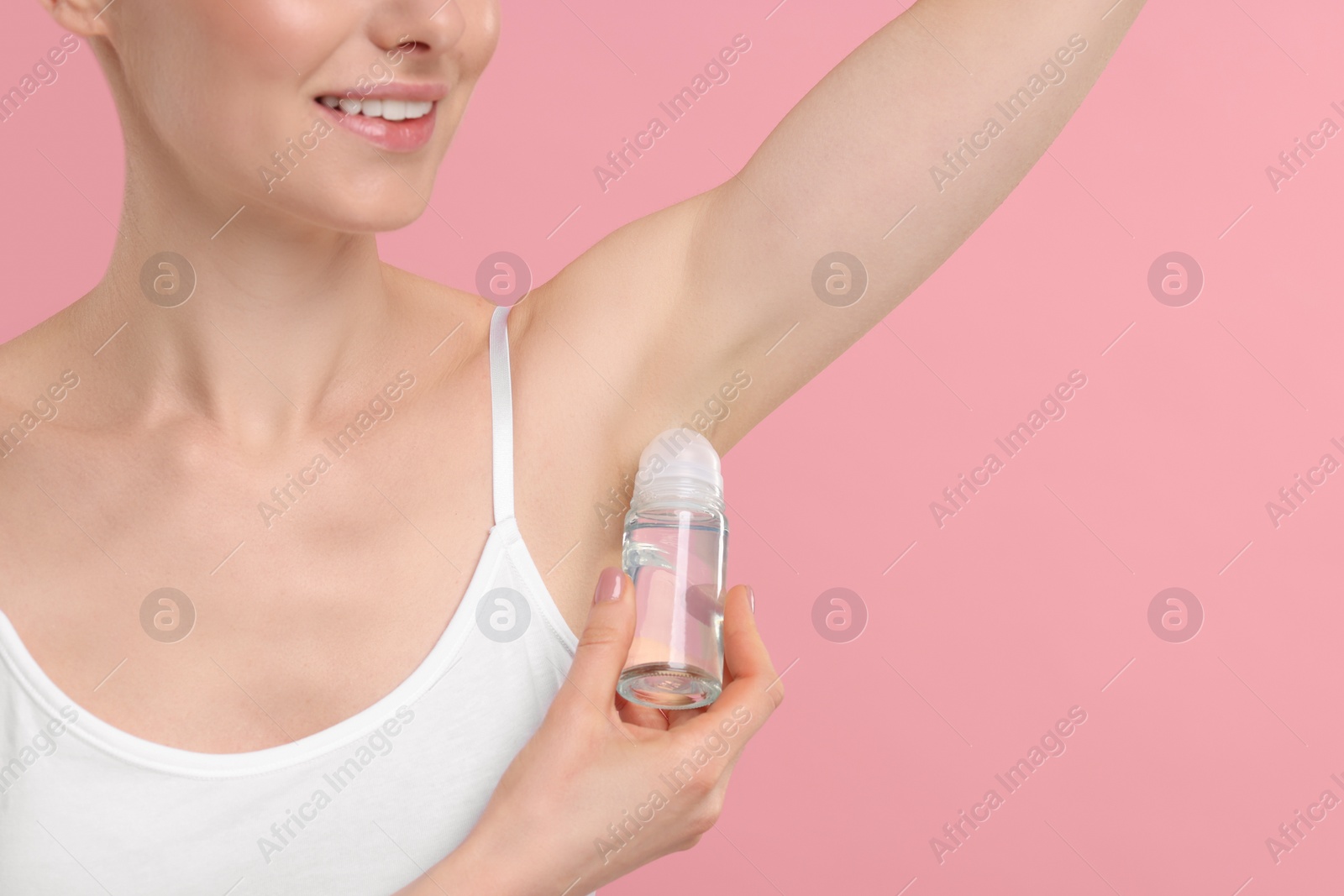 Photo of Woman applying deodorant on pink background, closeup