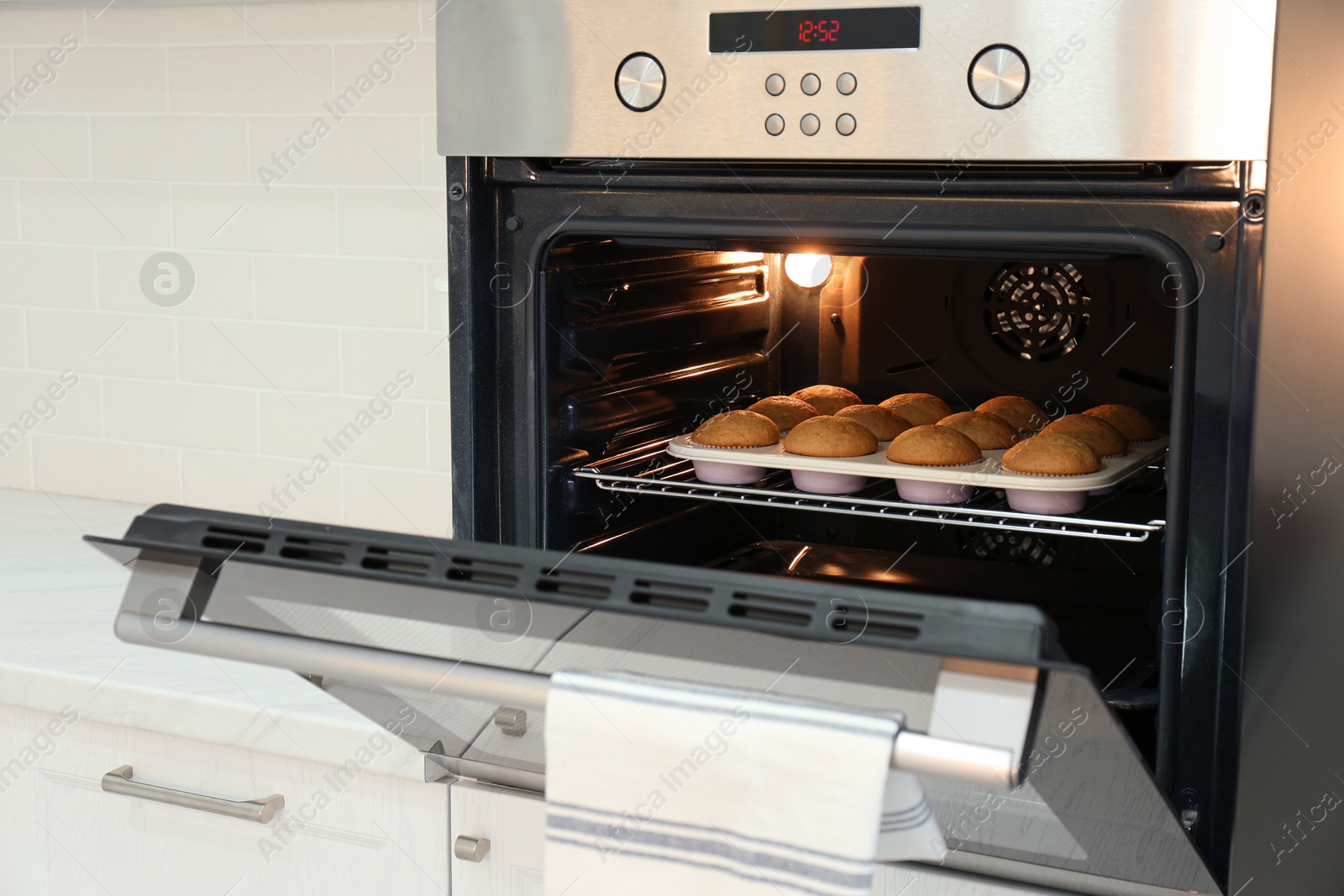 Photo of Baking pan with cupcakes in modern oven