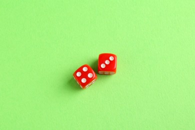Photo of Two red game dices on green background, flat lay