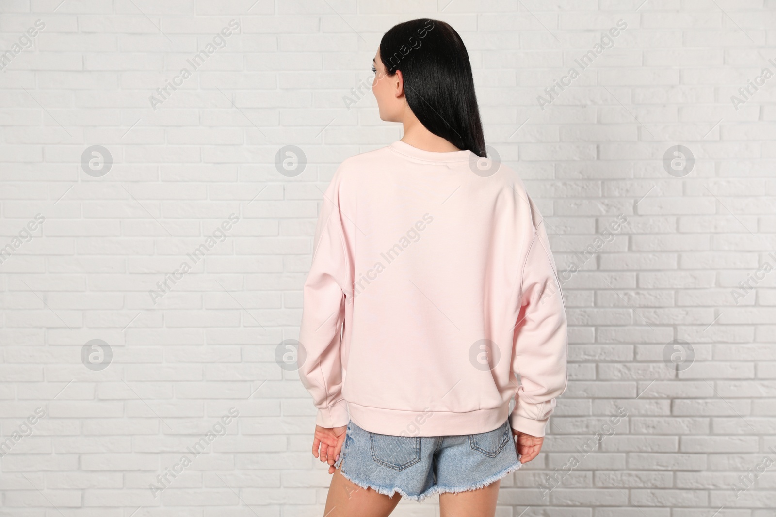 Photo of Young woman in sweater at brick wall. Mock up for design