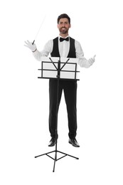 Happy professional conductor with baton and note stand on white background