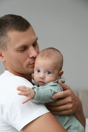 Photo of Father holding his cute baby on grey background