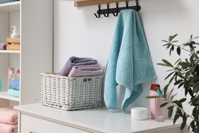 Fresh towels, laundry basket and toiletries on chest of drawers indoors