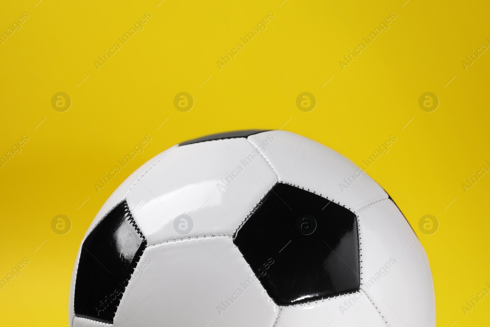 Photo of One soccer ball on yellow background, closeup. Sports equipment