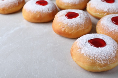 Photo of Hanukkah doughnuts with jelly and sugar powder on grey table, space for text