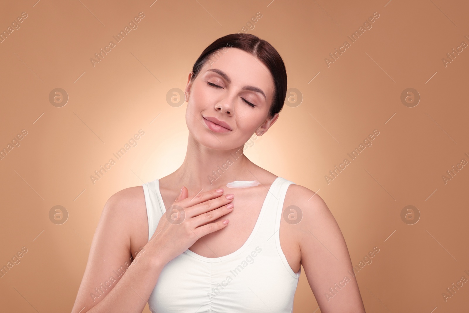 Photo of Beautiful woman with smear of body cream on her neck against light brown background