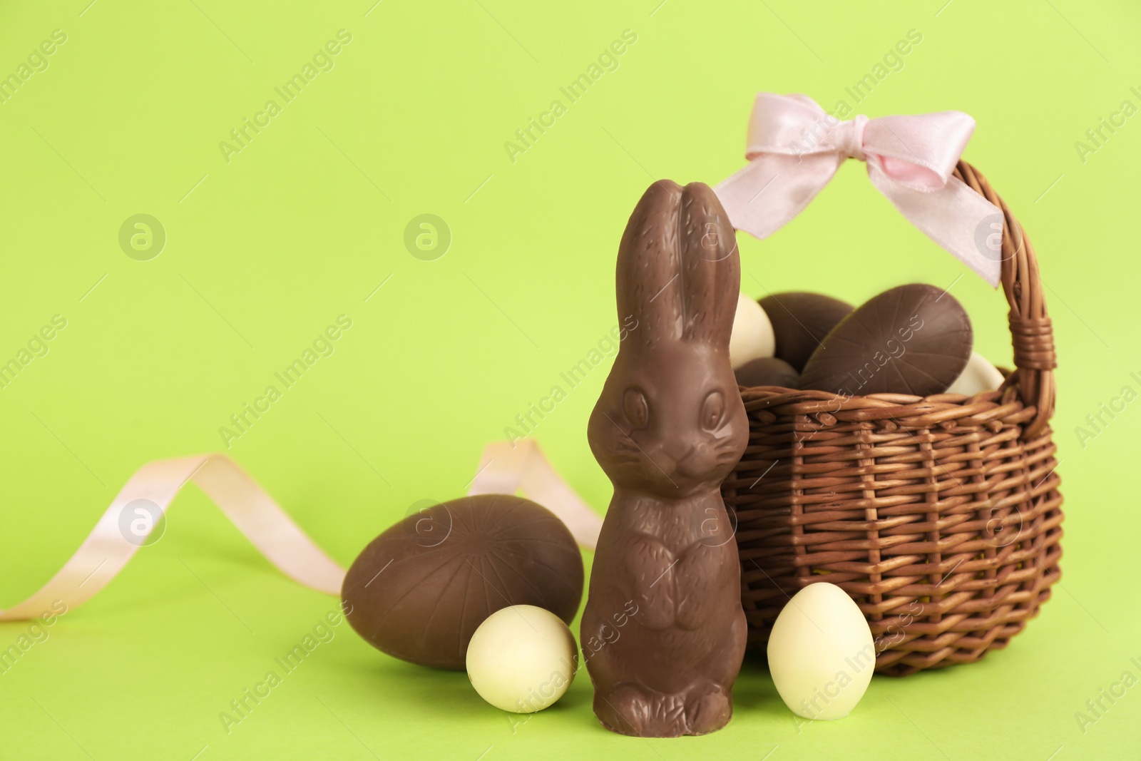 Photo of Chocolate Easter bunny and eggs on green background. Space for text