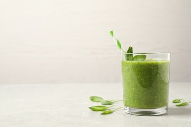 Green juice and fresh spinach leaves on light grey table. Space for text