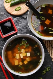 Delicious miso soup with tofu served on black textured table, flat lay