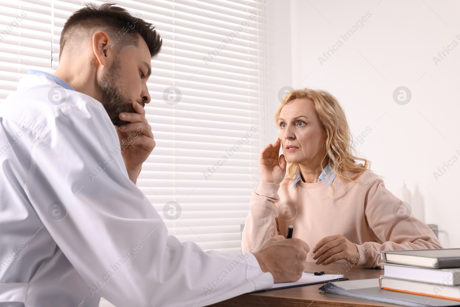 Photo of Doctor writing down patient's complaints during consultation in clinic