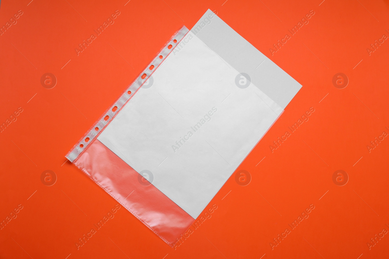 Photo of Punched pocket with paper sheet on orange background, top view. Space for text