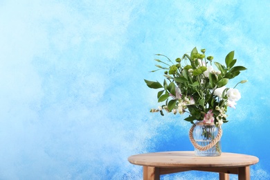 Photo of Vase with bouquet of beautiful flowers on table against color background. Space for text