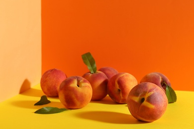 Photo of Fresh ripe peaches and green leaves on color background