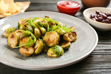 Photo of Delicious roasted brussels sprouts with arugula on table, closeup