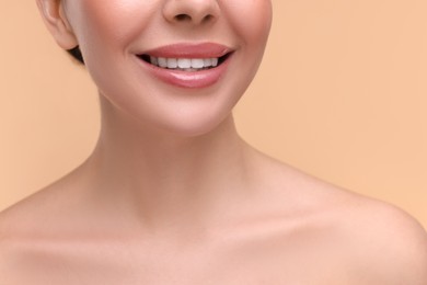 Photo of Woman with beautiful lips smiling on beige background, closeup