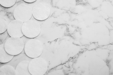 Many clean cotton pads on white marble table, flat lay. Space for text