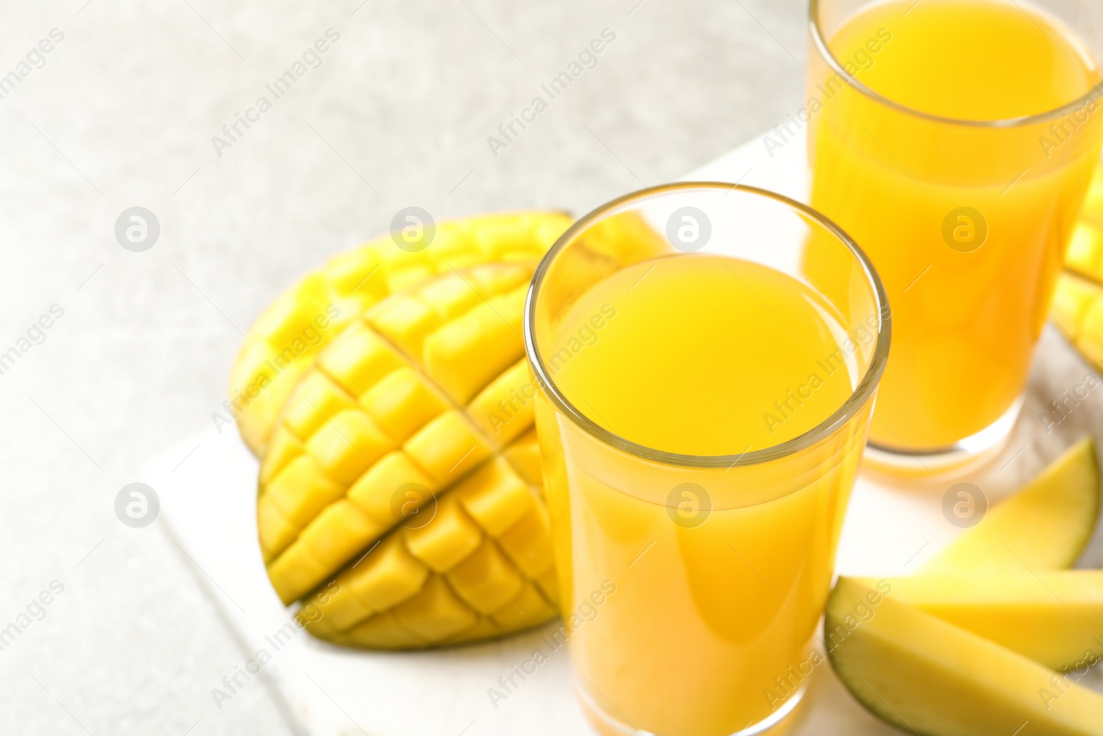 Photo of Fresh mango drink and cut fruits on table, closeup. Space for text