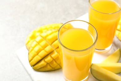 Fresh mango drink and cut fruits on table, closeup. Space for text