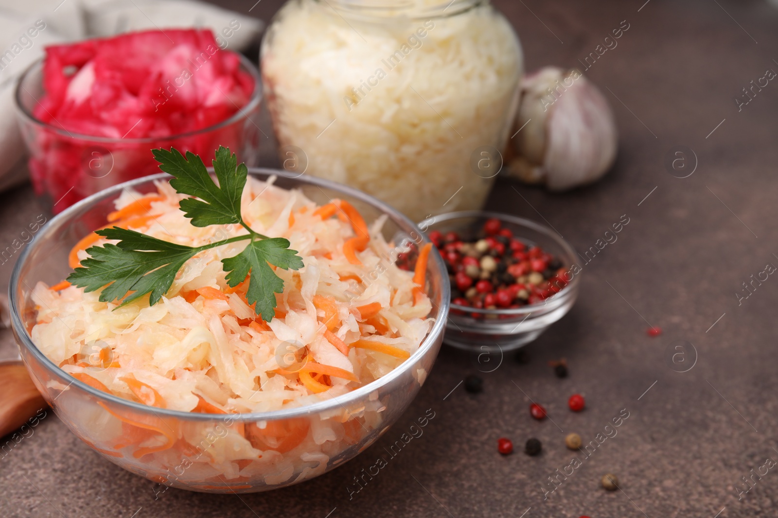 Photo of Delicious sauerkraut prepared according to different recipes on brown table, closeup. Space for text