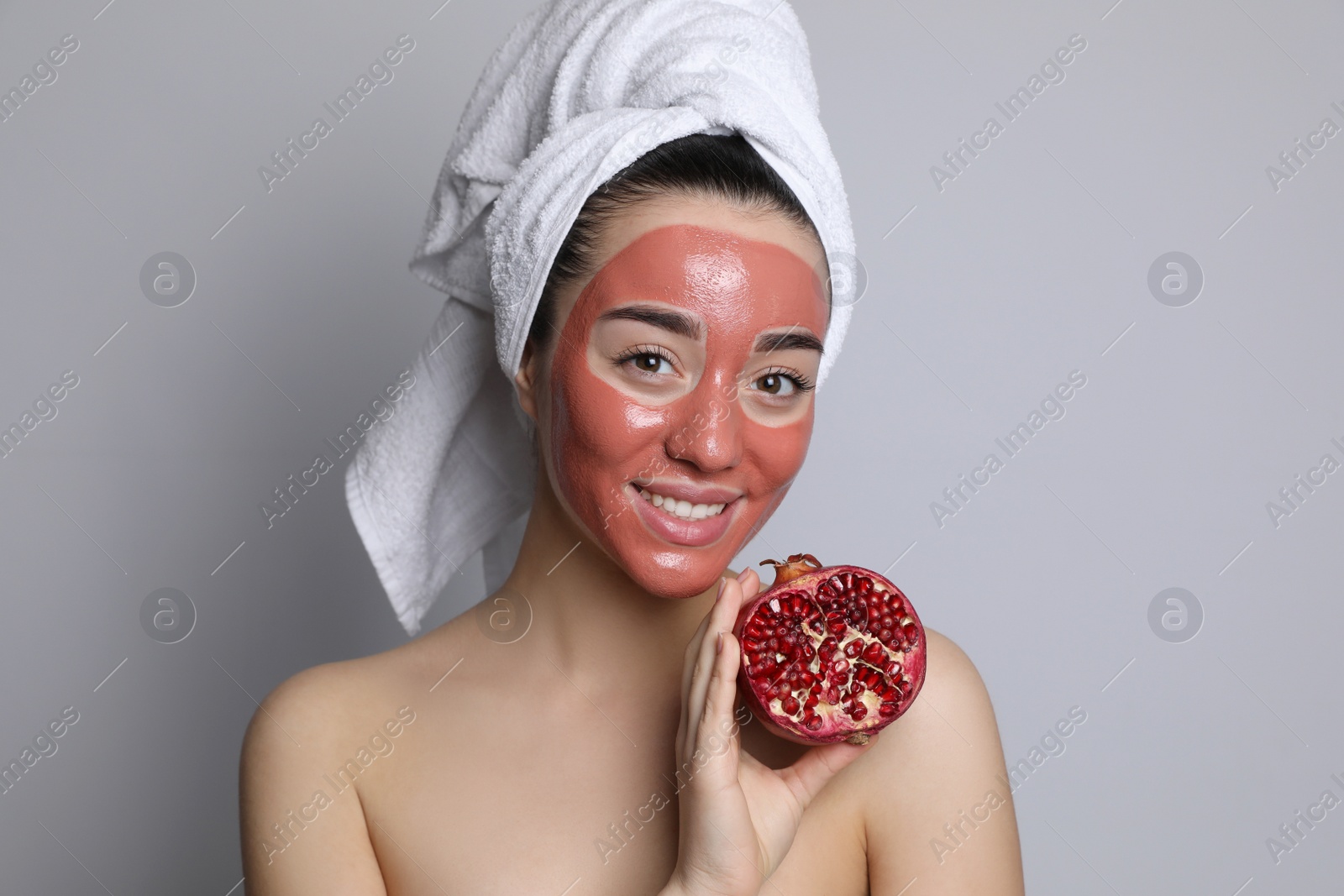 Photo of Woman with pomegranate face mask and fresh fruit on grey background