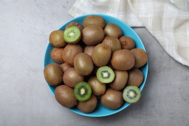 Photo of Fresh ripe kiwis in bowl on light grey table, top view