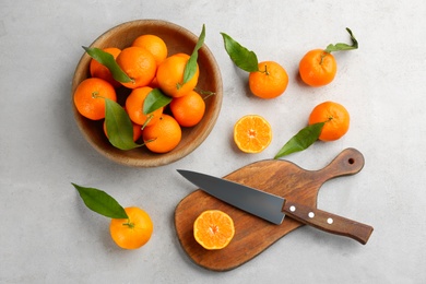 Photo of Fresh ripe tangerines with green leaves on light table, flat lay