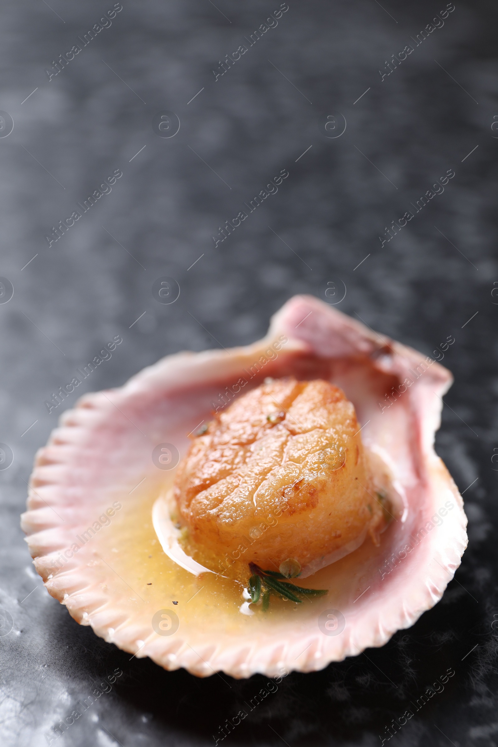 Photo of Delicious fried scallop in shell on black table