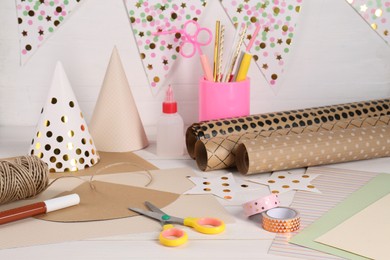 Photo of Stationery and different materials to create party hats on white wooden table. Handmade decoration