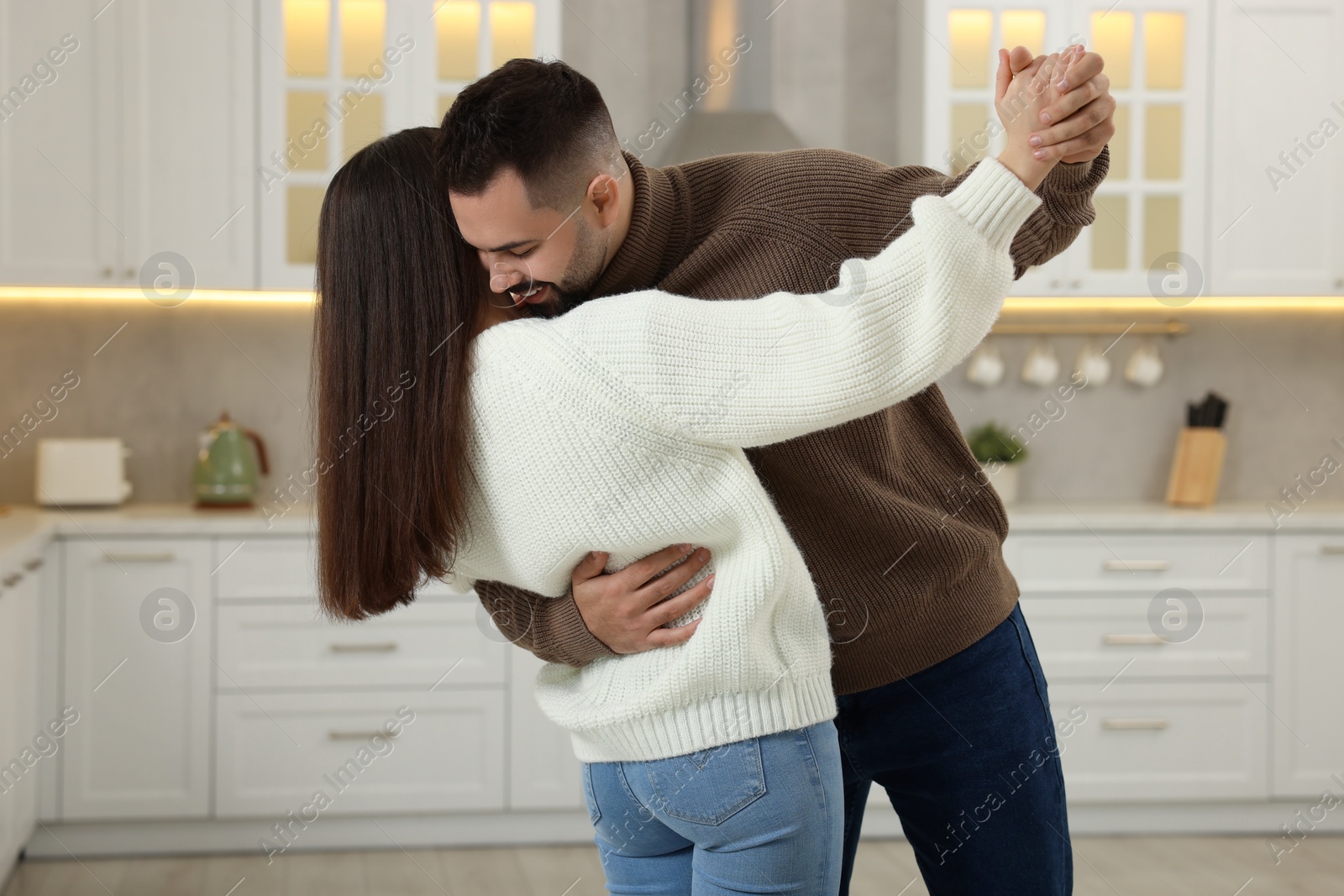 Photo of Affectionate young couple dancing in light kitchen