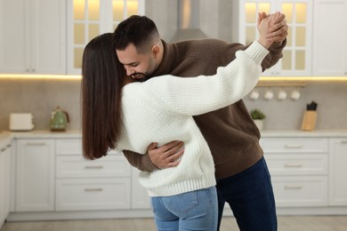 Affectionate young couple dancing in light kitchen