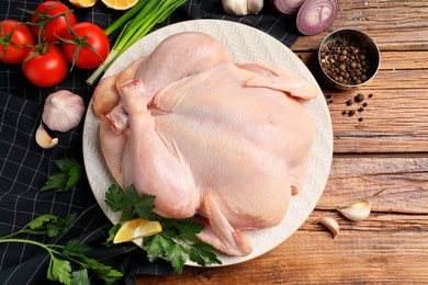 Fresh raw chicken with different products on wooden table, flat lay