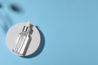 Bottle of cosmetic oil on light blue background, top view. Space for text