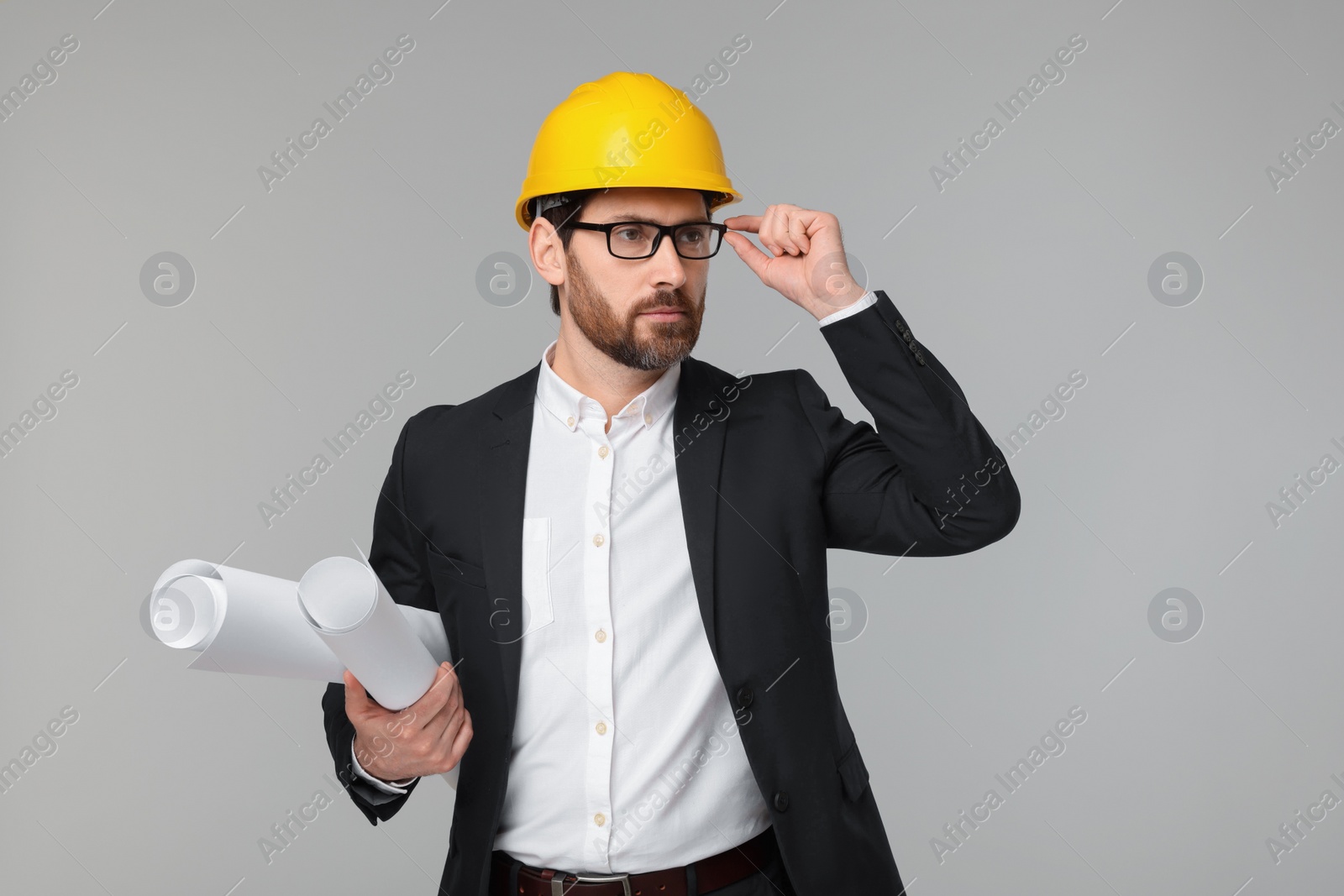 Photo of Architect in hard hat with drafts on gray background