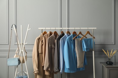 Photo of Rack with different stylish women`s clothes and bags near grey wall