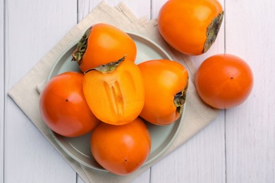 Delicious ripe juicy persimmons on white wooden table, flat lay