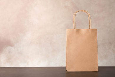 Mockup of paper shopping bag on table against color background