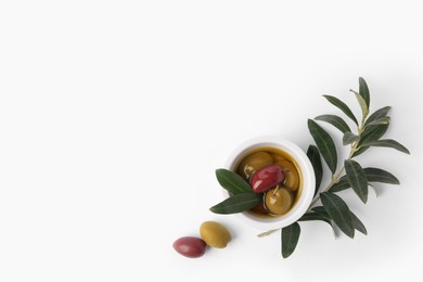 Bowl with different ripe olives and leaves on white background, flat lay. Space for text