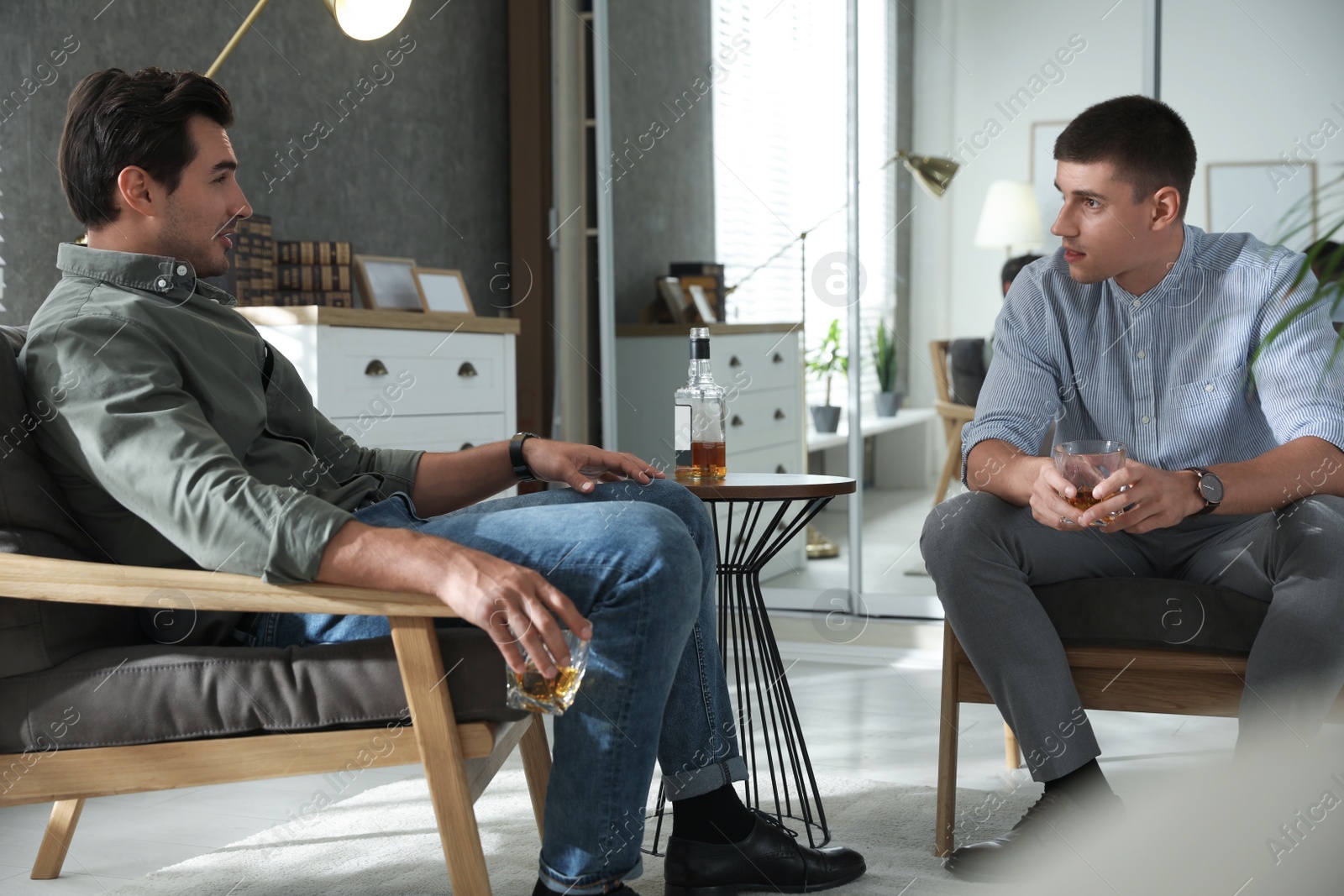 Photo of Young men drinking whiskey together at home