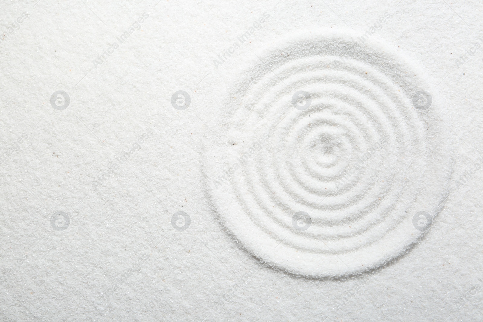 Photo of Zen rock garden. Circle pattern on white sand, top view