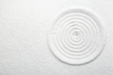 Photo of Zen rock garden. Circle pattern on white sand, top view