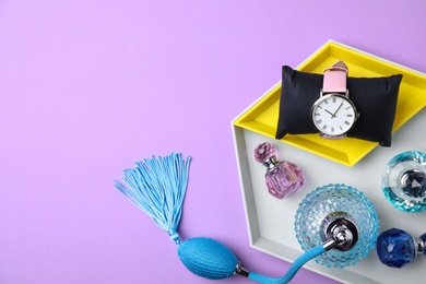 Flat lay composition with bottles of perfume and stylish female wristwatch on color background. Space for text
