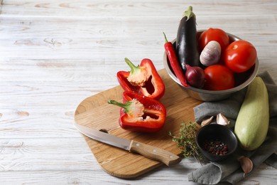 Photo of Cooking delicious ratatouille. Fresh ripe vegetables and bowl on white wooden table. Space for text