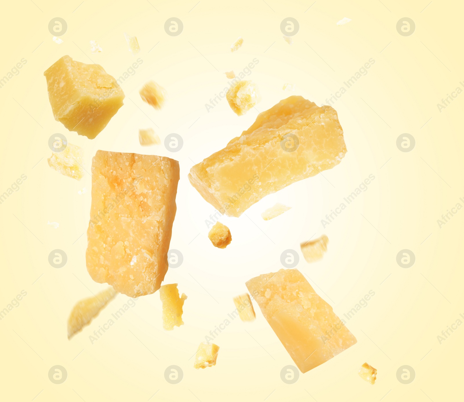 Image of Pieces of delicious parmesan cheese flying on beige background