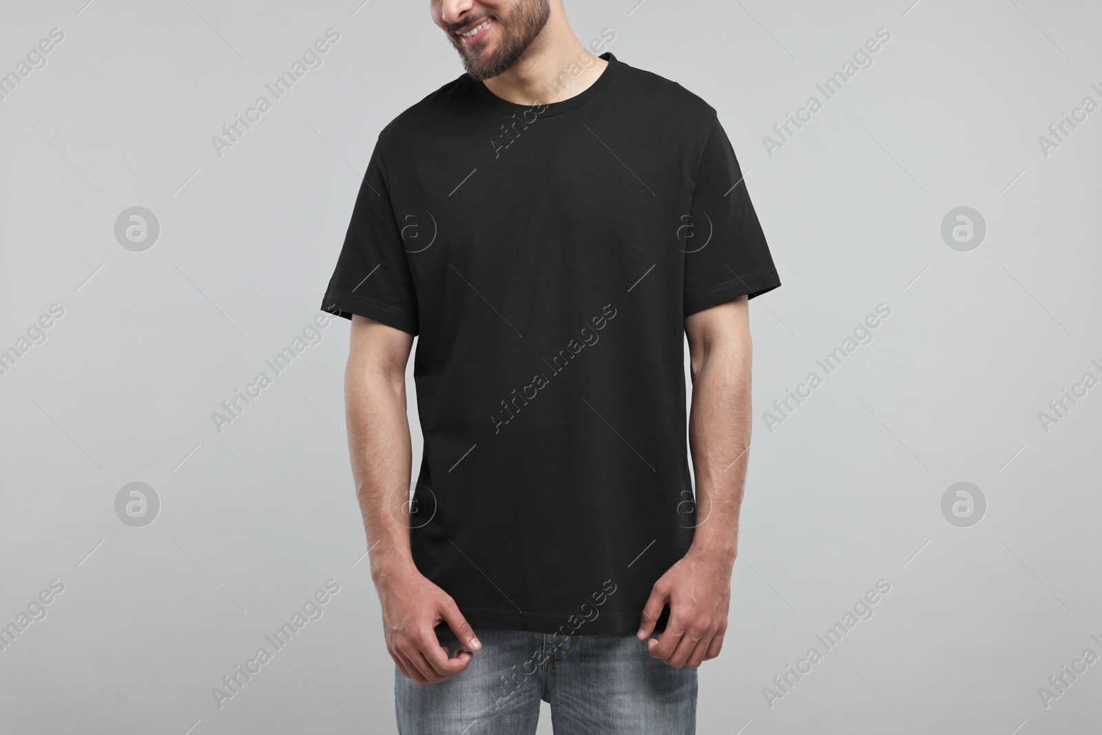 Photo of Smiling man in black t-shirt on grey background, closeup