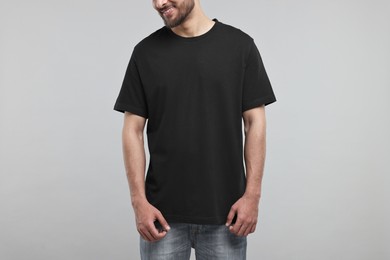 Smiling man in black t-shirt on grey background, closeup